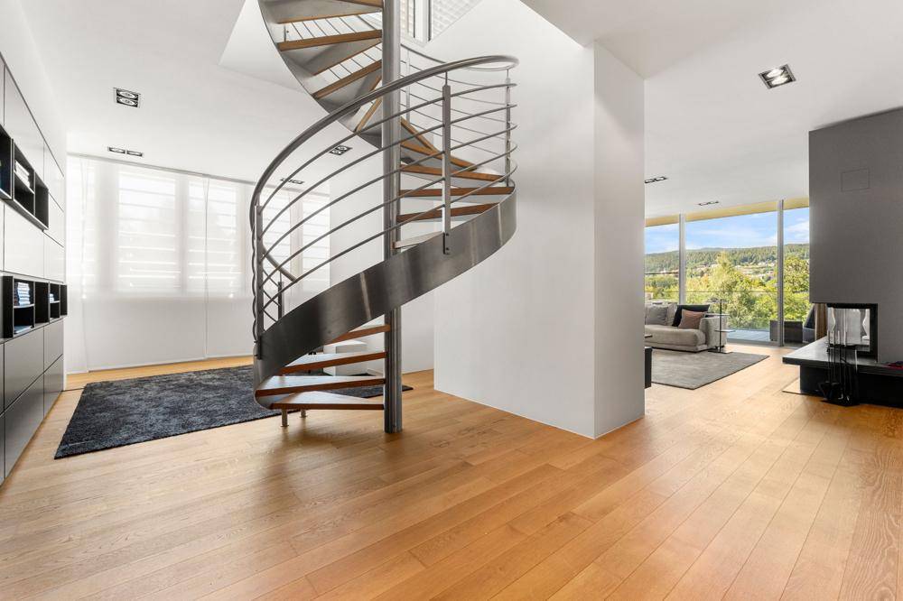 Heller Bereich mit eleganter Wendeltreppe und Holzboden, der zum Wohnbereich führt.