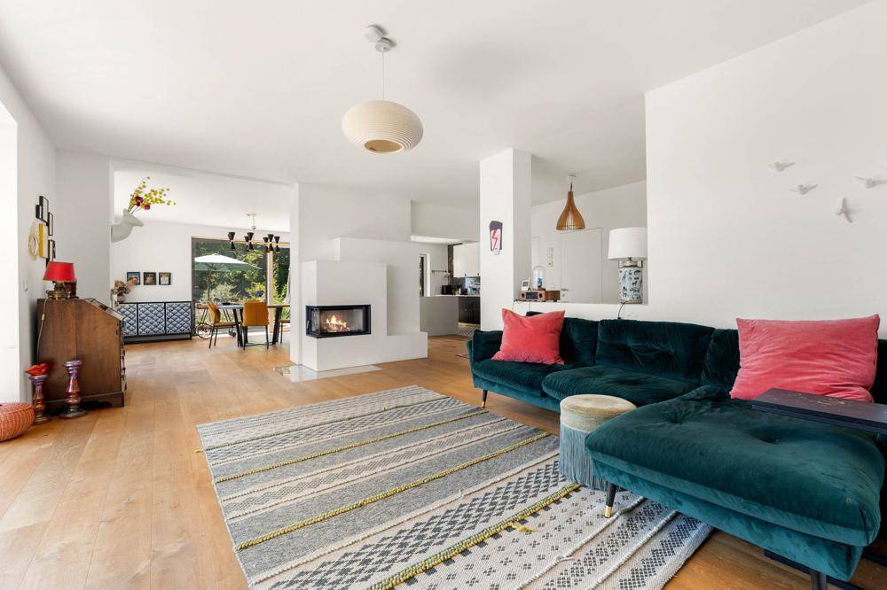 Gemütlicher Wohnbereich mit Kamin, bequemer Couch und Blick in den offenen Essbereich.