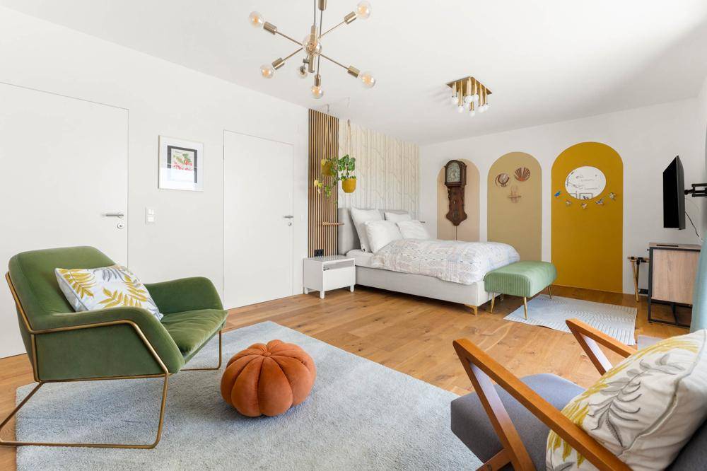 Modernes Schlafzimmer mit Holzboden, farbigen Akzenten und stilvoller Beleuchtung.