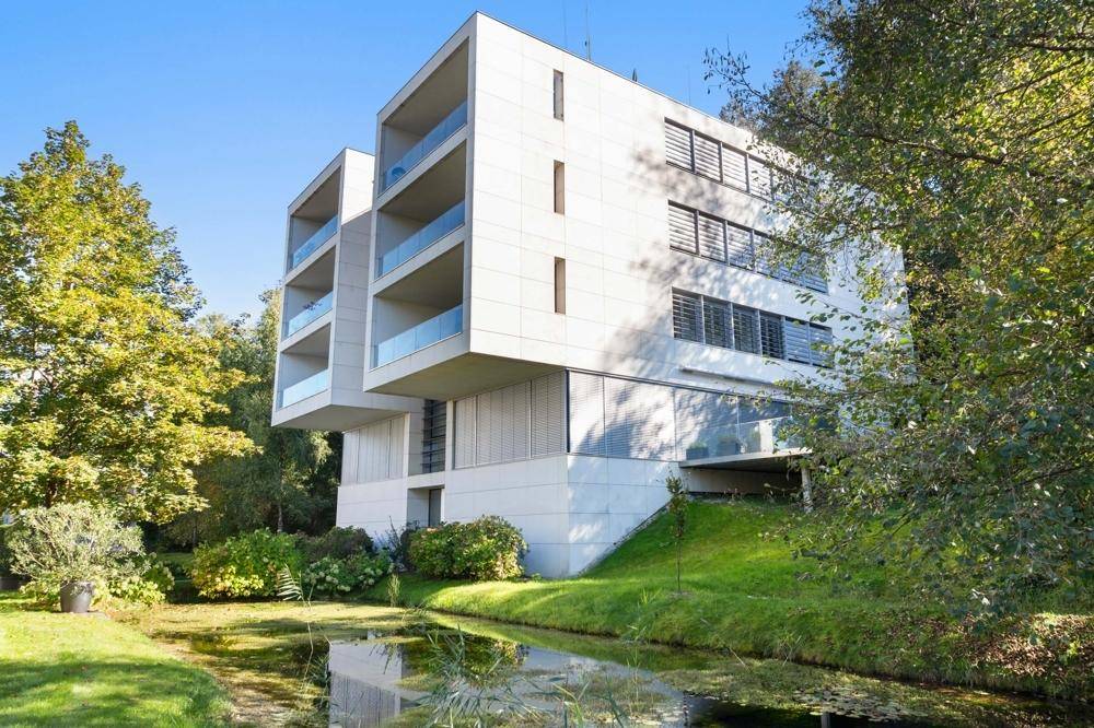 Zeitgenössische Architektur mit klaren Linien, Balkonen und einer idyllischen Lage am Wasser.
