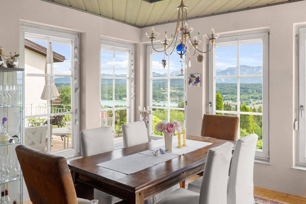 Heller Essbereich mit Holztisch und Stühlen, bietet einen weiten Blick auf See und Berge.