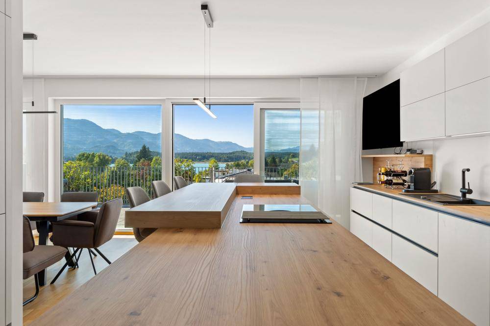 Helle Küche mit Kochinsel und großzügigem Fensterbereich, der einen Seeblick bietet.