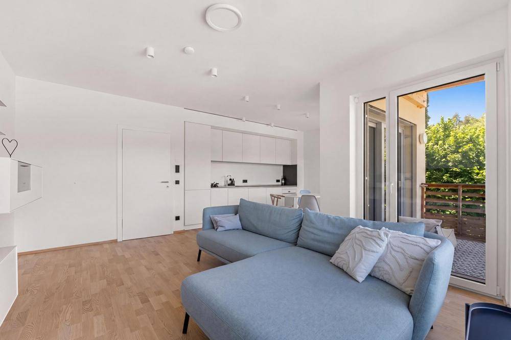 Moderner Wohnbereich mit integrierter Küche und direktem Zugang zu einem Balkon.