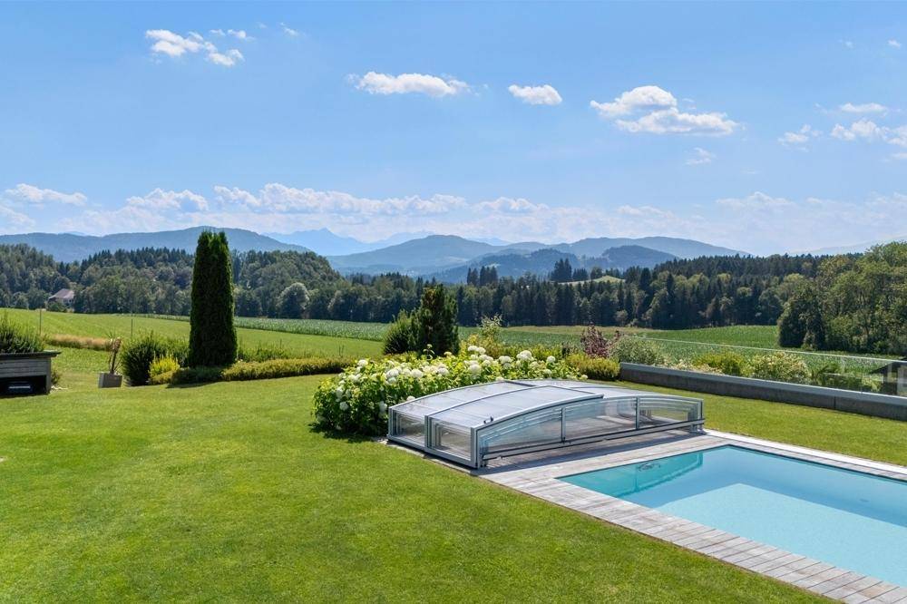 Gepflegter Garten mit Pool und atemberaubendem Fernblick auf die umliegende Berglandschaft.