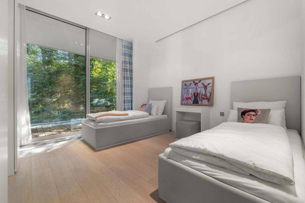 Helles Kinder- oder Gästezimmer mit zwei Einzelbetten und großen Fenstern zum Gartenbereich.