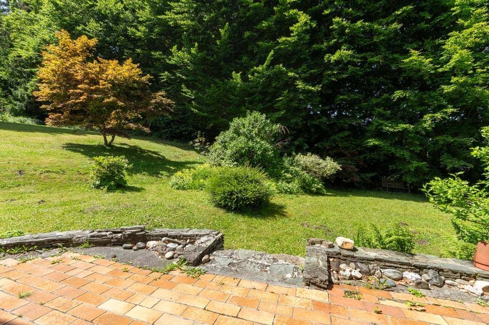 Sonniger Gartenbereich mit Terrasse und üppiger Vegetation, ideal zum Entspannen.