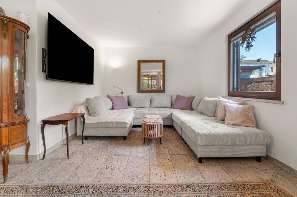 Komfortables Wohnzimmer mit großer Eckcouch, Flachbildfernseher und Blick ins Grüne.
