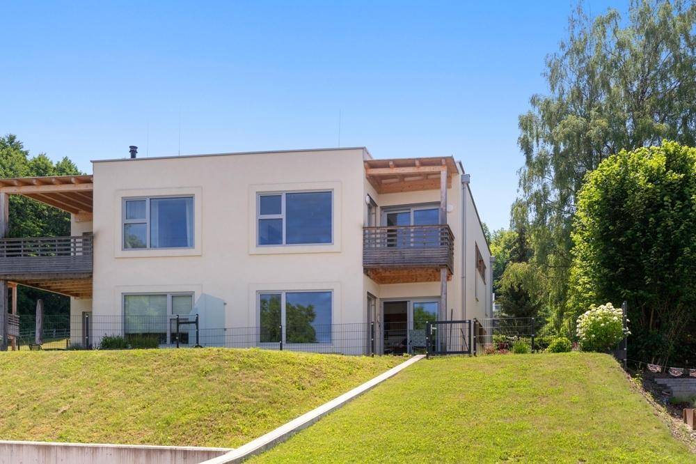 Modernes Gebäude mit mehreren Balkonen und einer gepflegten Rasenfläche.