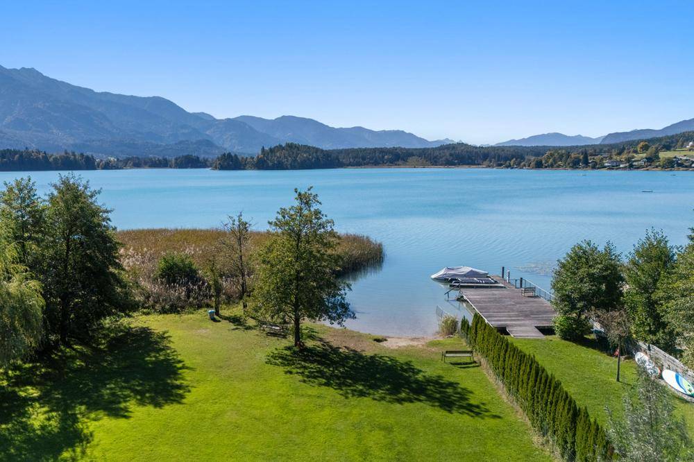 Großer grüner Gartenbereich mit direktem Zugang zu einem See und einem privaten Steg.