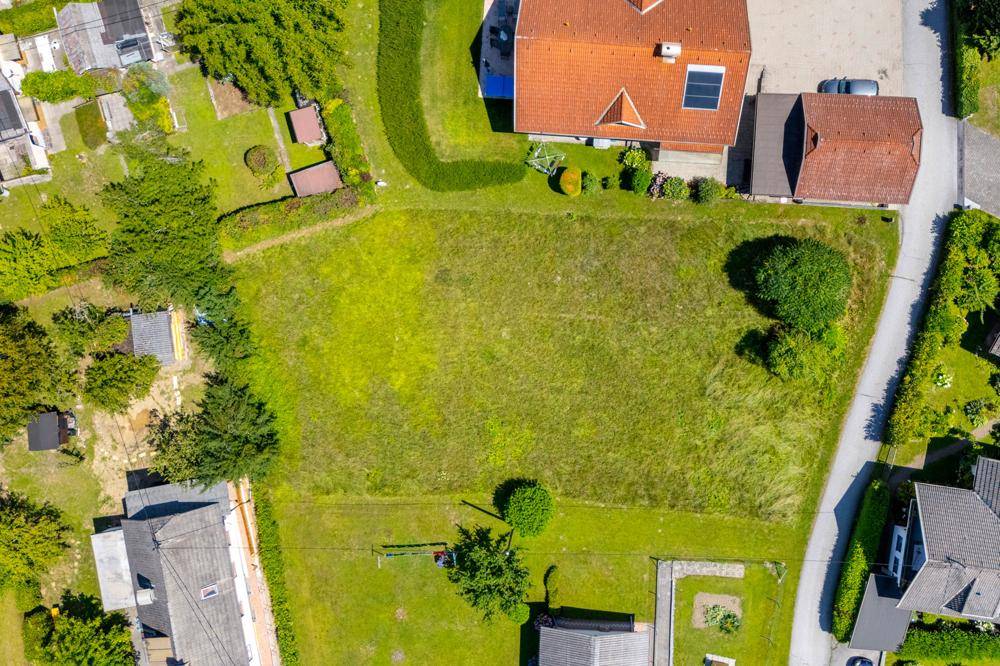 Direkte Draufsicht auf ein großes, grünes Baugrundstück in einer Wohnsiedlung.
