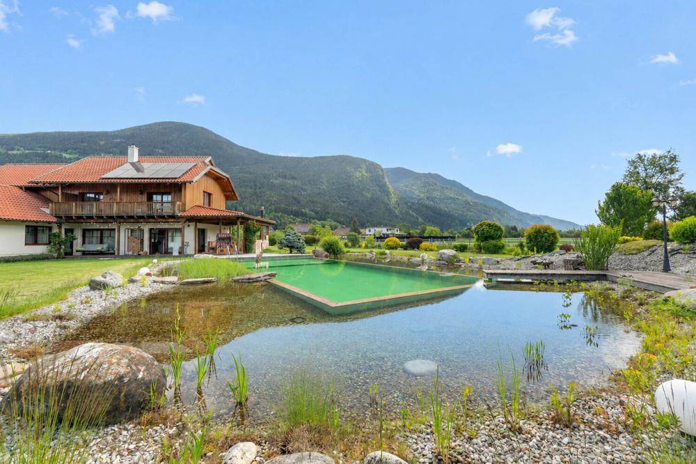 Weitläufiger Garten mit Naturpool, großem Teich und Panoramablick auf die Berge.