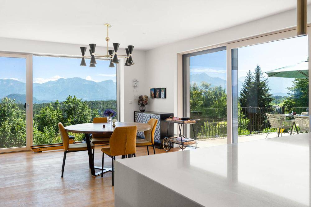 Heller Essbereich mit großen Fenstern, die einen weiten Blick auf die Berge und die Terrasse bieten.