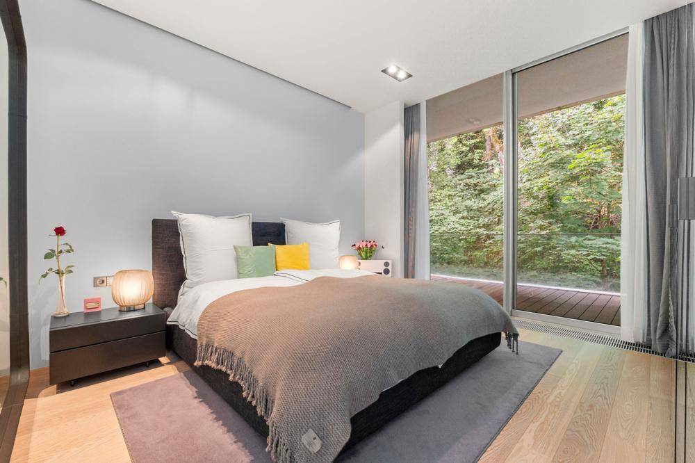 Gemütliches Schlafzimmer mit großem Bett und raumhohen Fenstern mit direktem Blick ins Grüne.