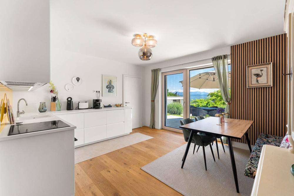 Helle Küche mit weißen Schränken, Essbereich und Zugang zur Terrasse mit Bergblick.