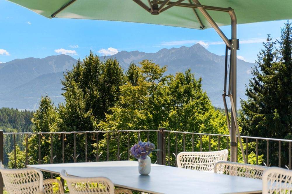 Gemütliche Terrasse mit Esstisch und Sonnenschirm, bietet einen direkten Blick auf die Berge.
