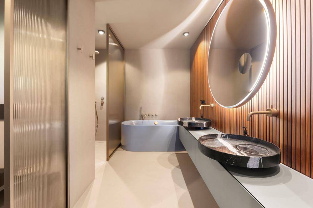 Luxuriöses Badezimmer mit freistehender Wanne, zwei Marmorwaschbecken und modernem, beleuchtetem Spiegel.