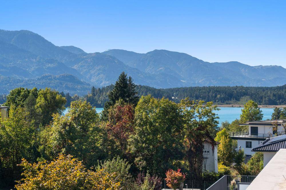 Panoramablick auf den See und die umliegende Berglandschaft mit üppiger Vegetation.