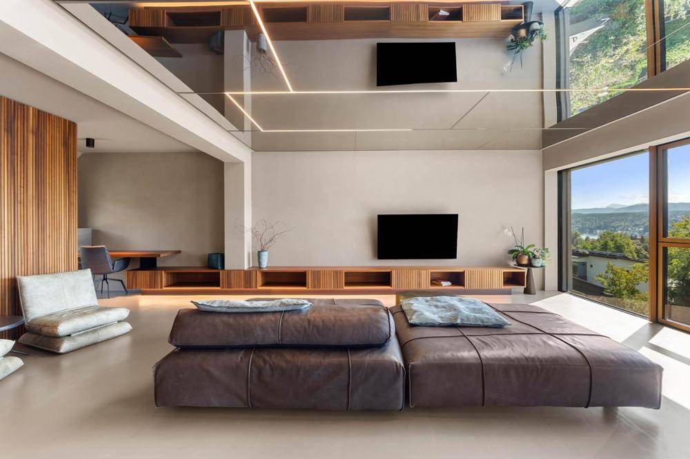Geräumiges, offenes Wohnzimmer mit moderner Einrichtung und reflektierender Decke, die den Raum vergrößert.