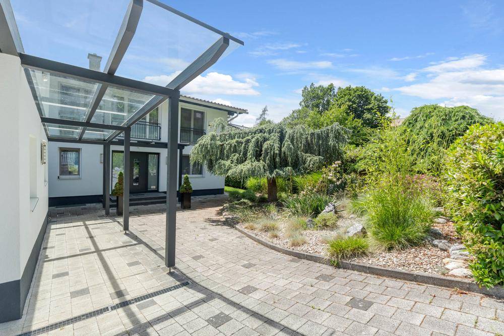 Gepflasterte Auffahrt mit Carport und gepflegtem Vorgartenbereich des Hauses.