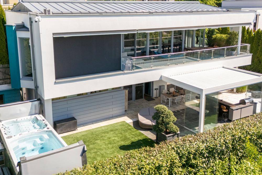 Luftaufnahme der modernen Villa mit Whirlpool, kleiner Rasenfläche und großzügiger Terrasse mit Sonnenschutz.