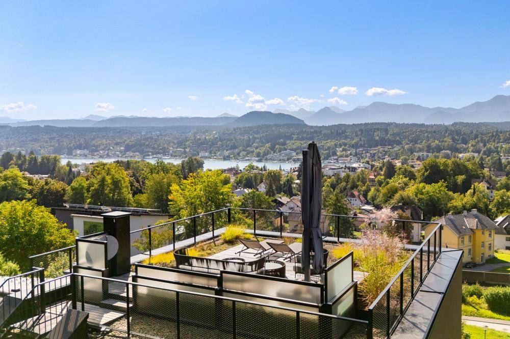 Weitläufige Dachterrasse mit Bepflanzung und Sitzgelegenheiten, umgeben von einer malerischen Landschaft.
