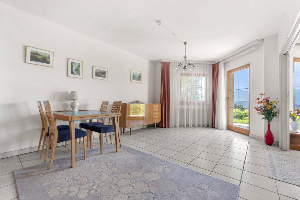 Heller Essbereich mit Fliesenboden, einem Esstisch und Zugang zu einem Balkon mit Aussicht.