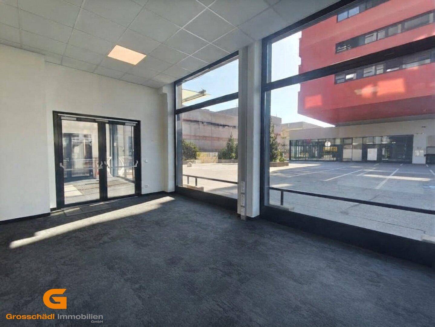Heller Gewerberaum mit Eingangstüren und Blick auf den Außenbereich und moderne Gebäude.
