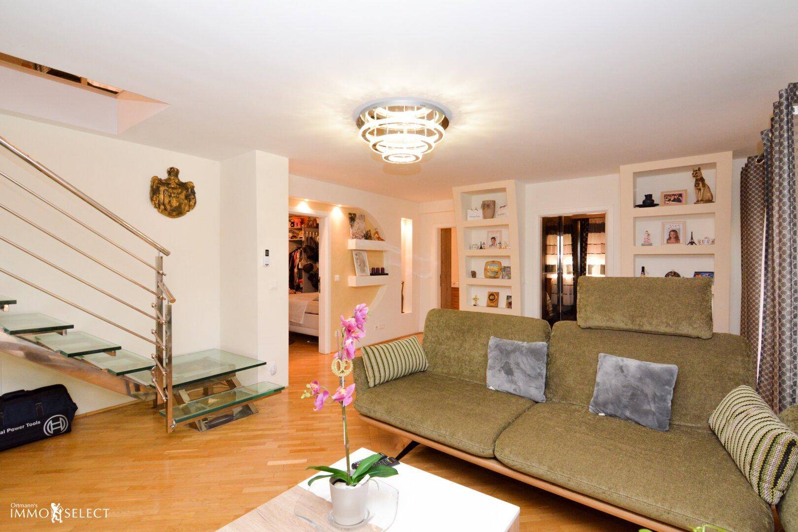 Heller Wohnbereich mit Holzboden, bequemer Couch und offener Treppe zum Obergeschoss.