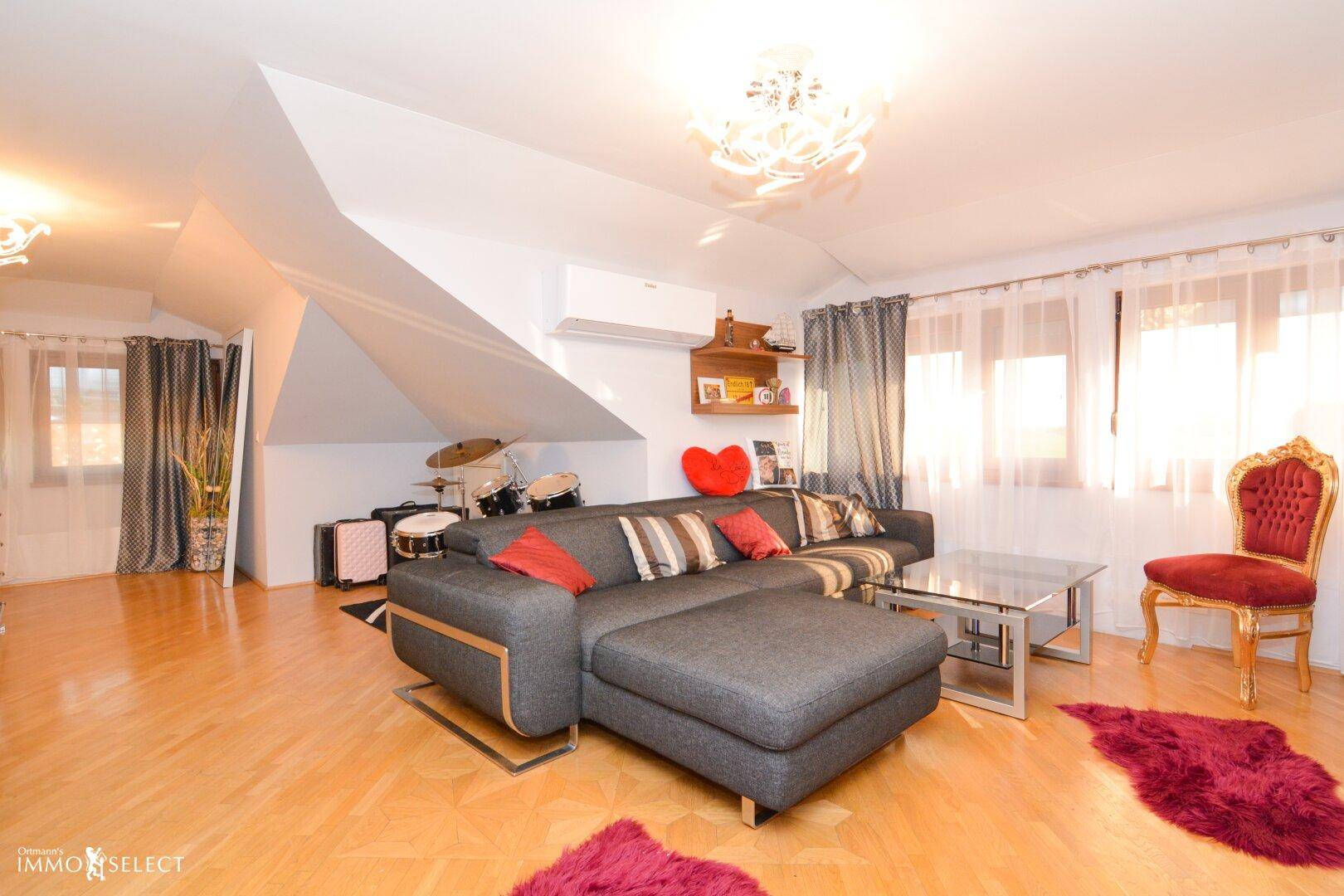 Geräumiges Wohnzimmer mit Holzboden, Ecksofa und Zugang zu einem Balkon.