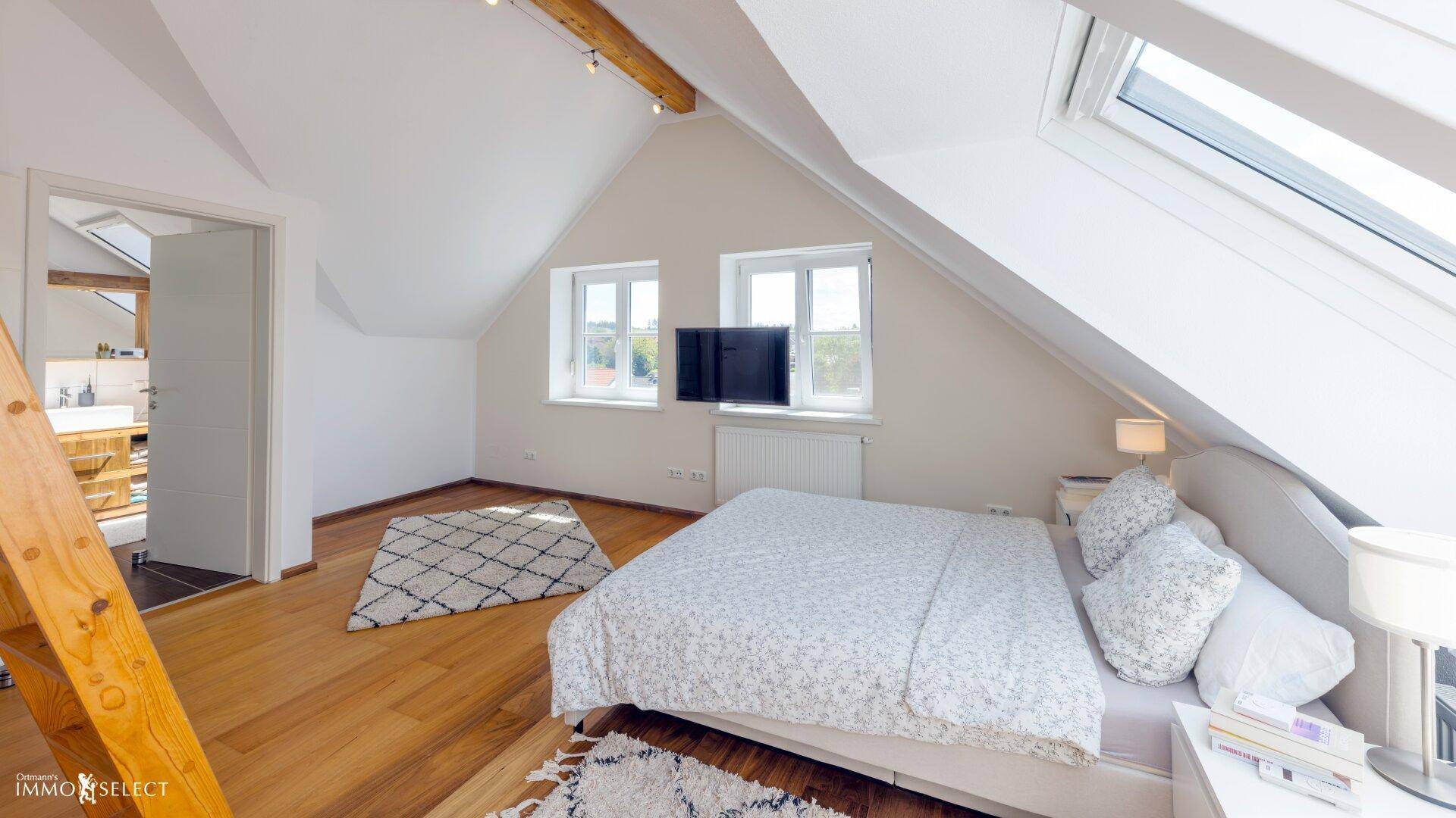 Helles Schlafzimmer im Dachgeschoss mit Holzboden, Dachfenstern und Blick ins Grüne.