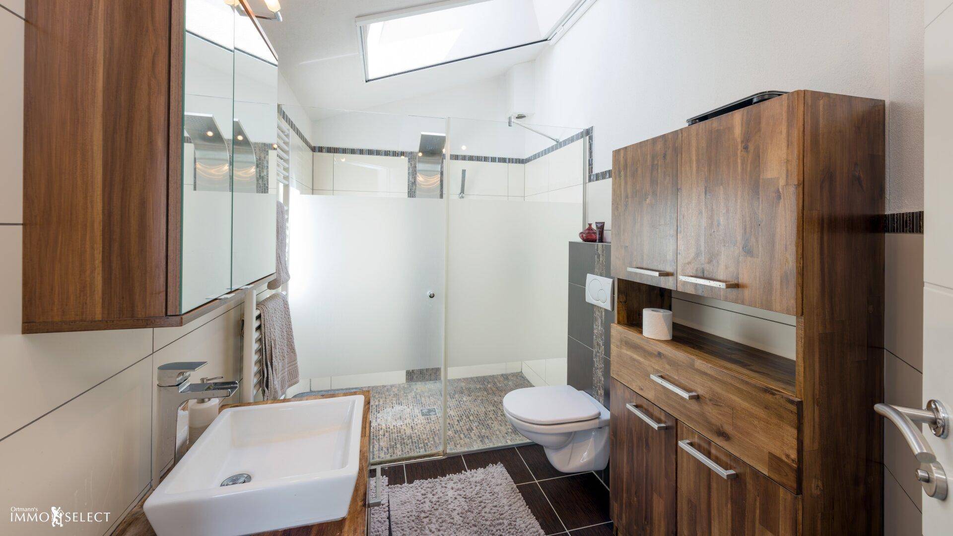 Modernes Badezimmer mit begehbarer Dusche, Holzmöbeln und Dachfenster.