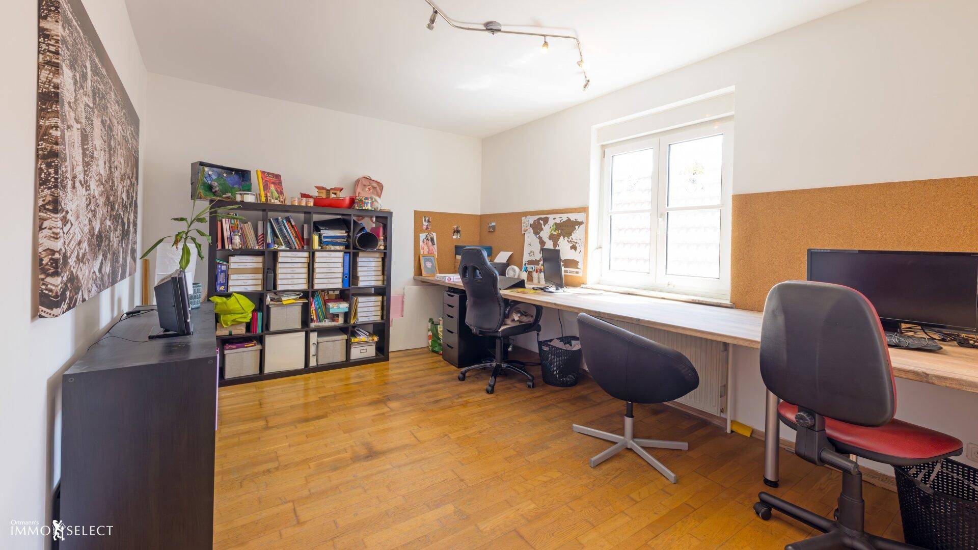 Großes Arbeitszimmer mit Holzboden, mehreren Schreibtischen und viel Stauraum.