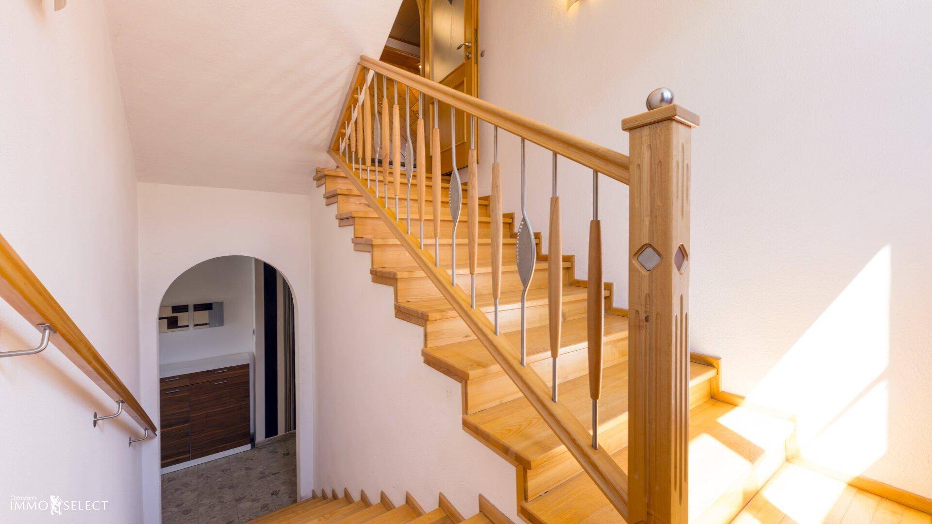 Elegante Holztreppe mit Metallgeländer, die die verschiedenen Etagen verbindet.