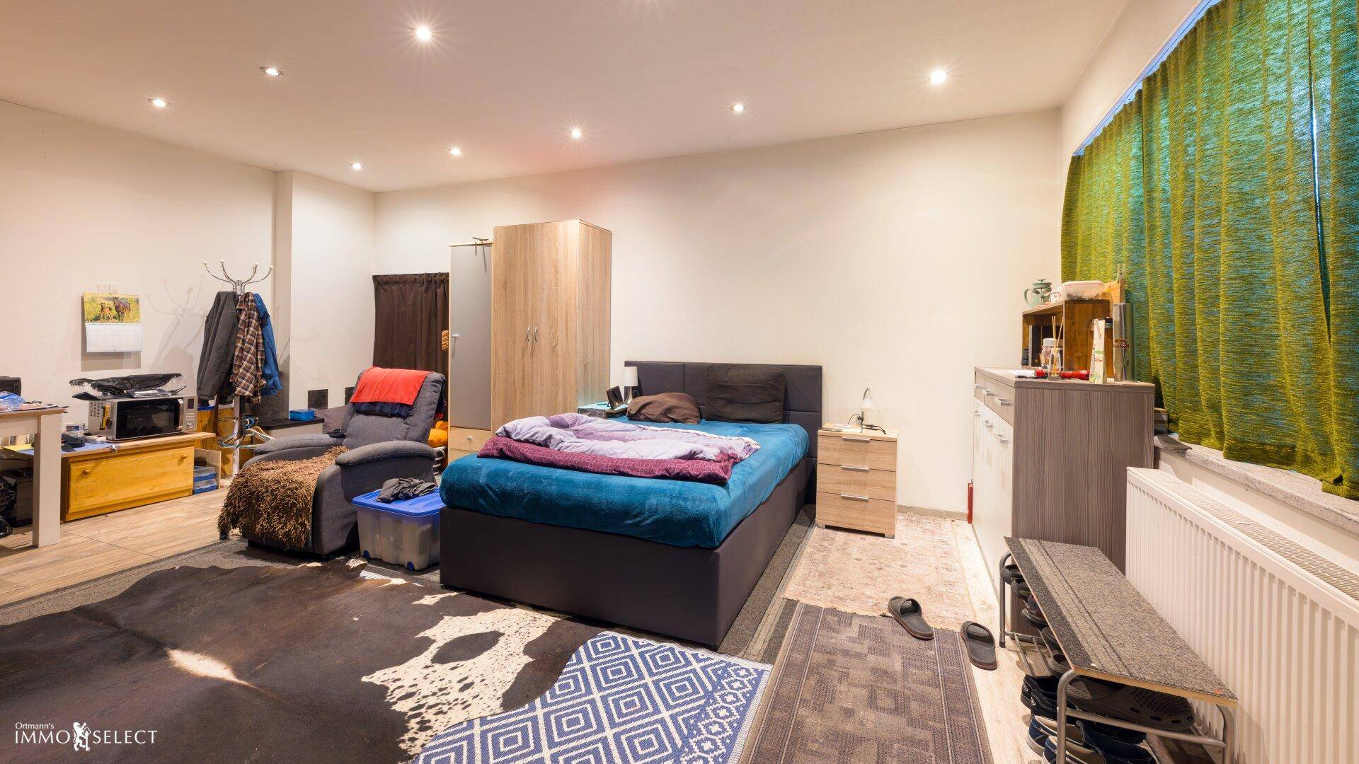 Geräumiges Schlafzimmer mit Doppelbett, Kleiderschrank und Teppichboden, gut beleuchtet und komfortabel.