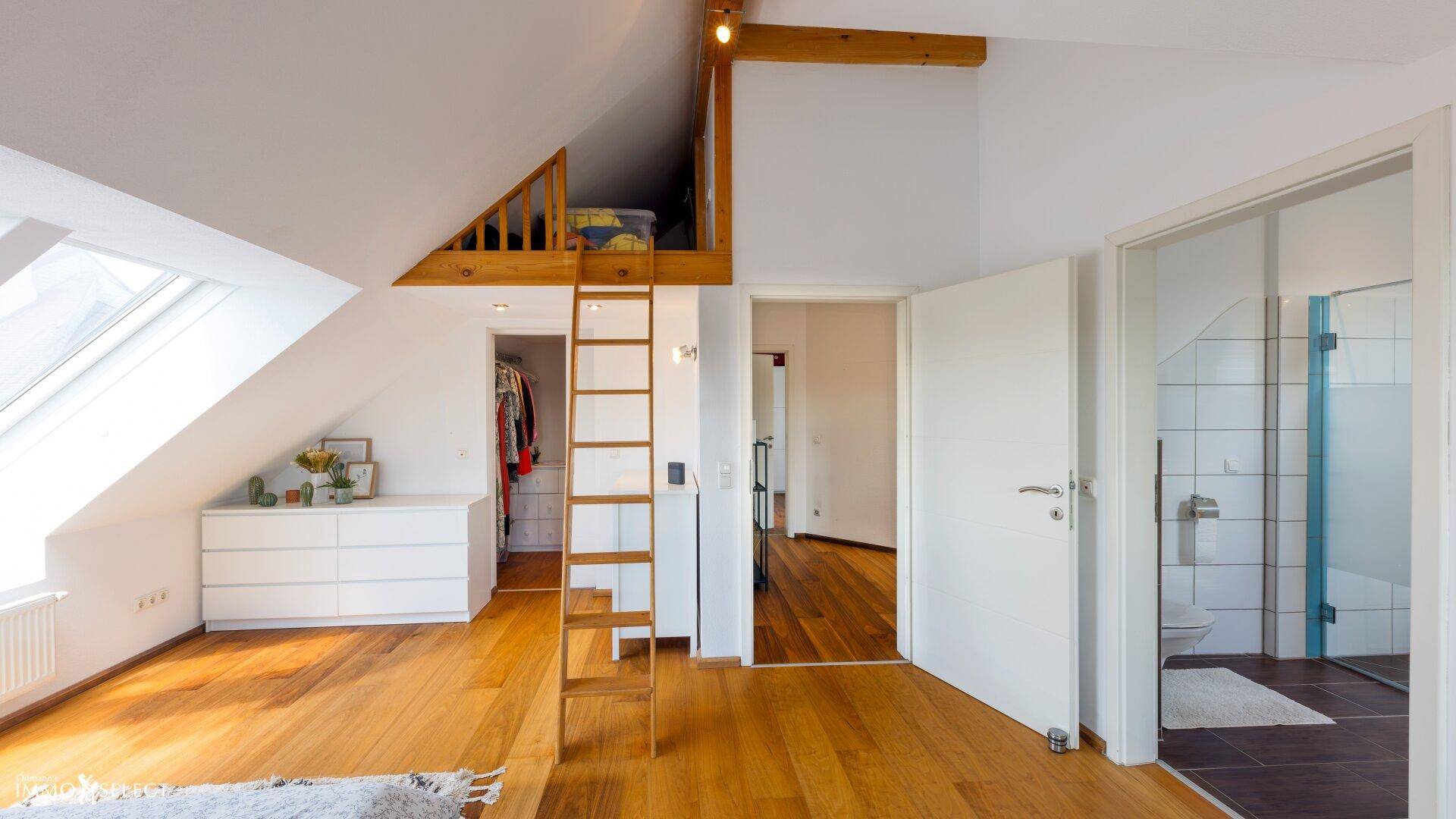 Schlafzimmer mit Holzboden, Hochbett, begehbarem Kleiderschrank und Zugang zum Bad.