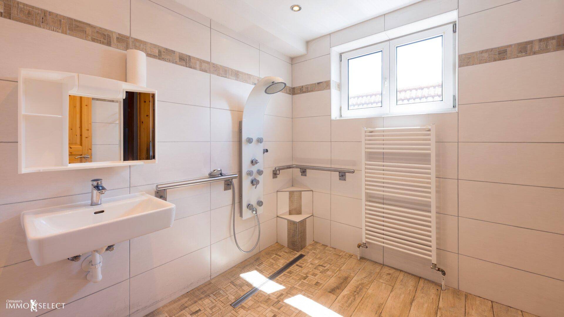 Modernes Badezimmer mit begehbarer Dusche, Haltegriffen und Fenster.
