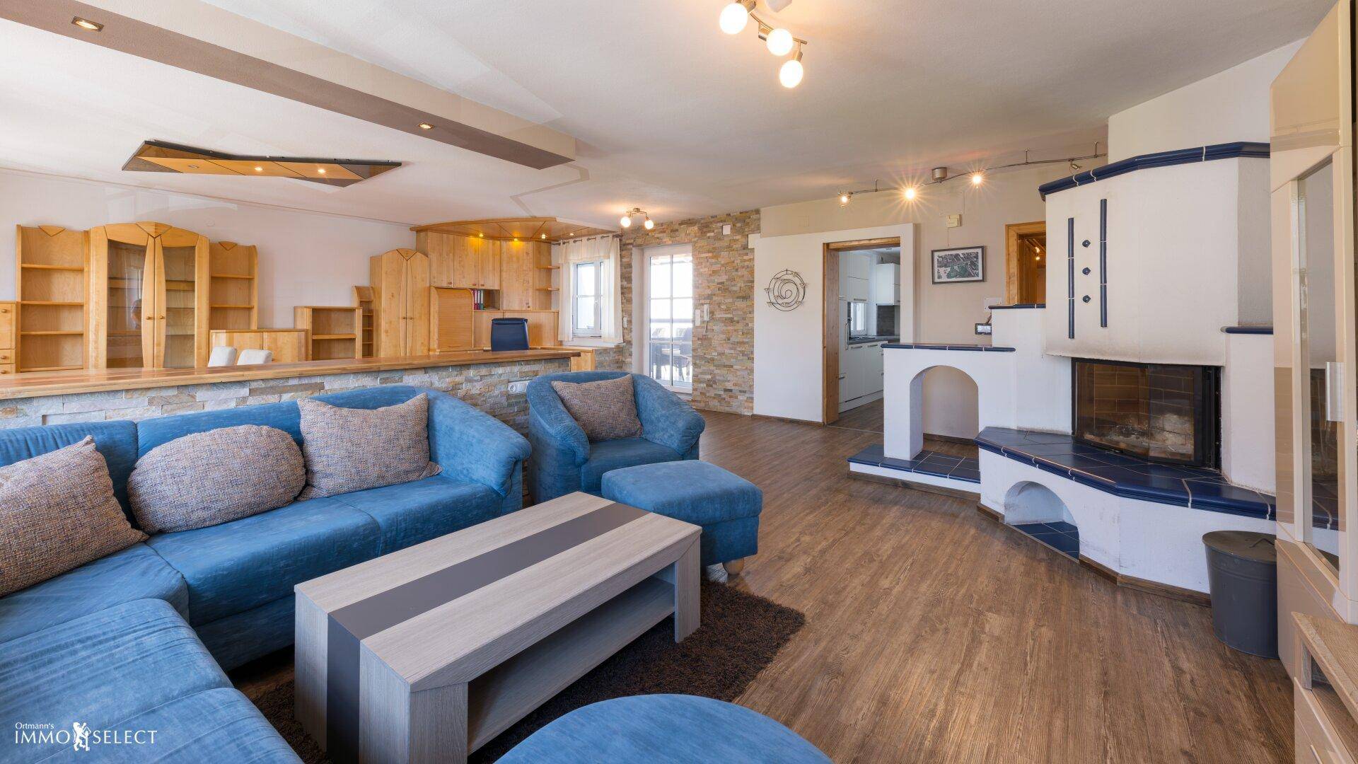 Gemütliches Wohnzimmer mit blauem Sofa, Kamin und rustikalen Steinwänden, ideal zum Entspannen.
