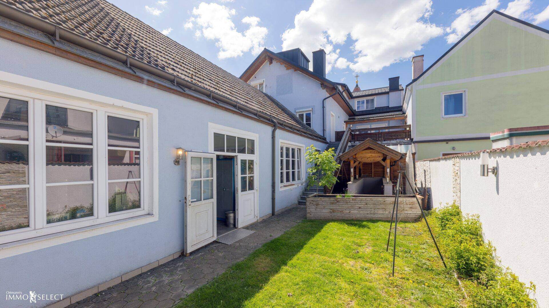 Hinterhof mit Rasenfläche, Gartenhaus und Zugang zum Gebäude, ideal für Entspannung im Freien.
