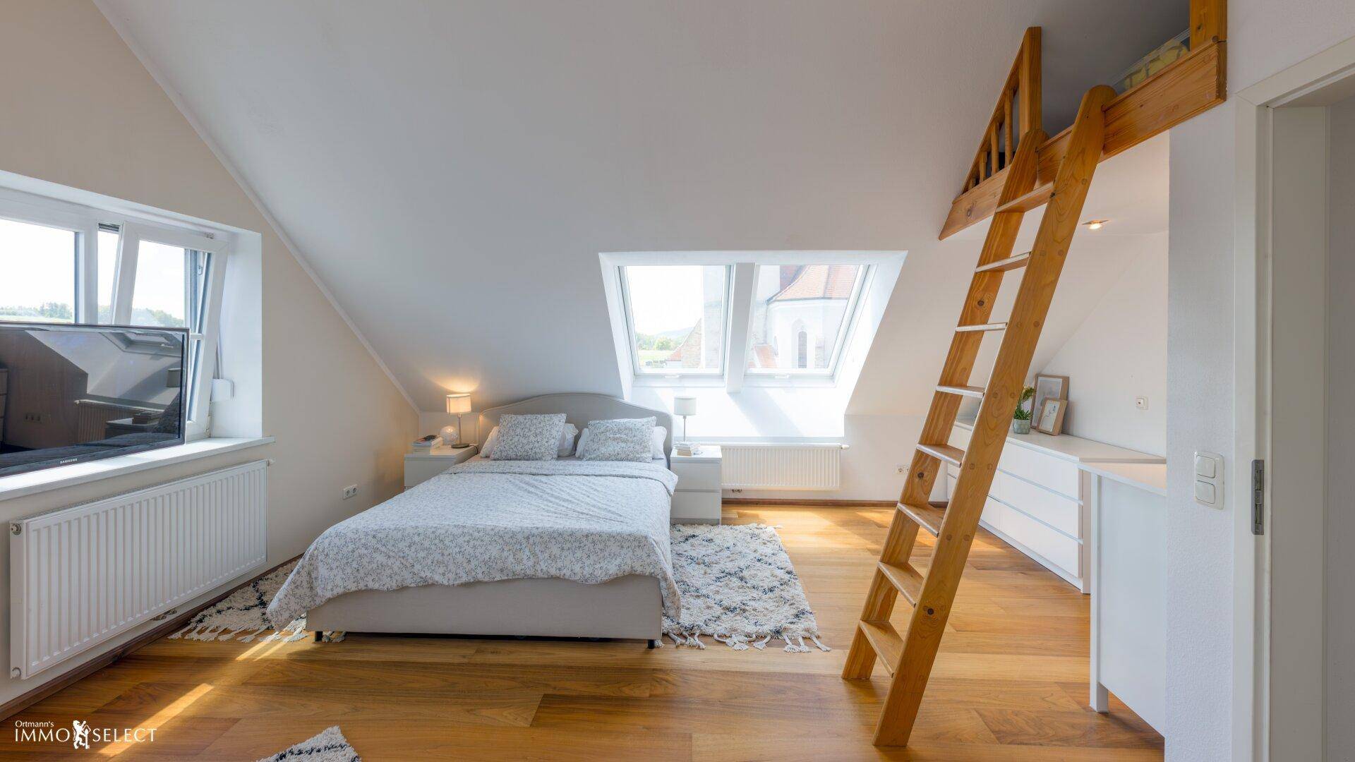 Helles Schlafzimmer im Dachgeschoss mit Holzboden, Dachfenstern und Hochbett.