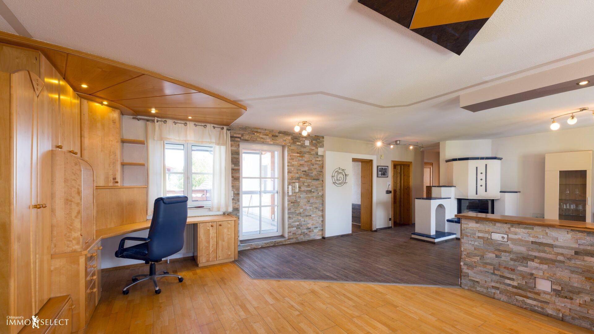 Geräumiger Arbeitsbereich mit Holzeinbauten, Steinwänden und Zugang zum Balkon, ideal für Homeoffice.