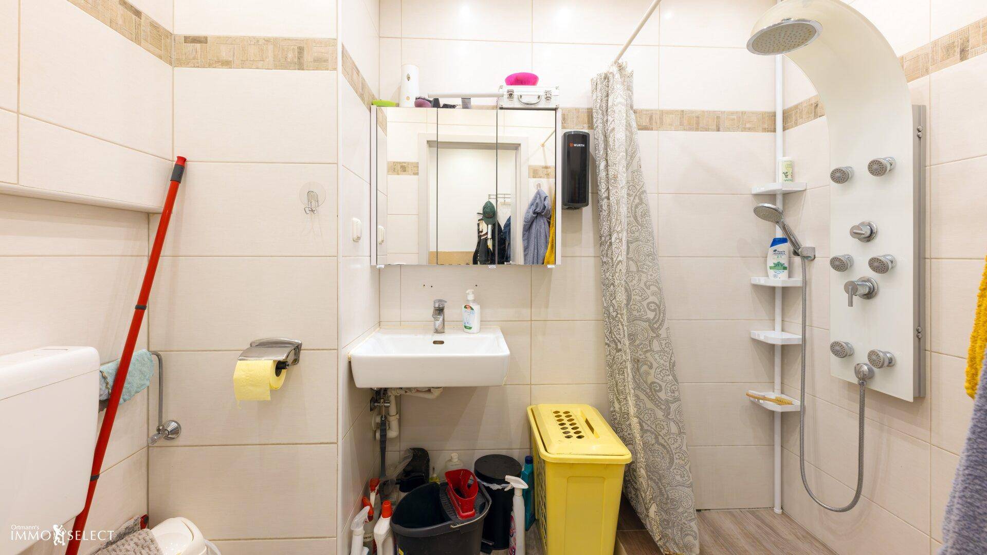 Modernes Badezimmer mit Duschpaneel, Waschbecken und hellen Fliesen, sauber und funktional.