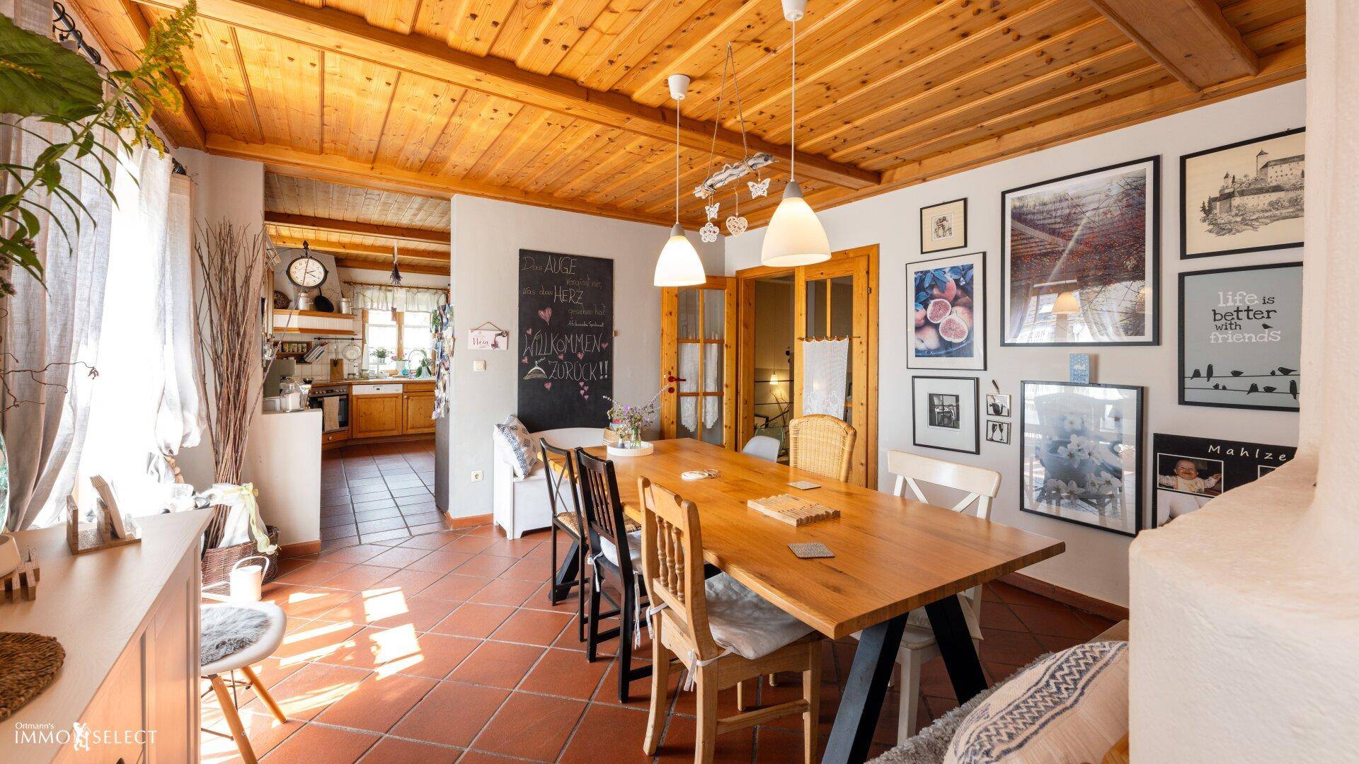 Gemütlicher Essbereich mit großem Holztisch, Terrakottaboden und Blick in die angrenzende Küche.