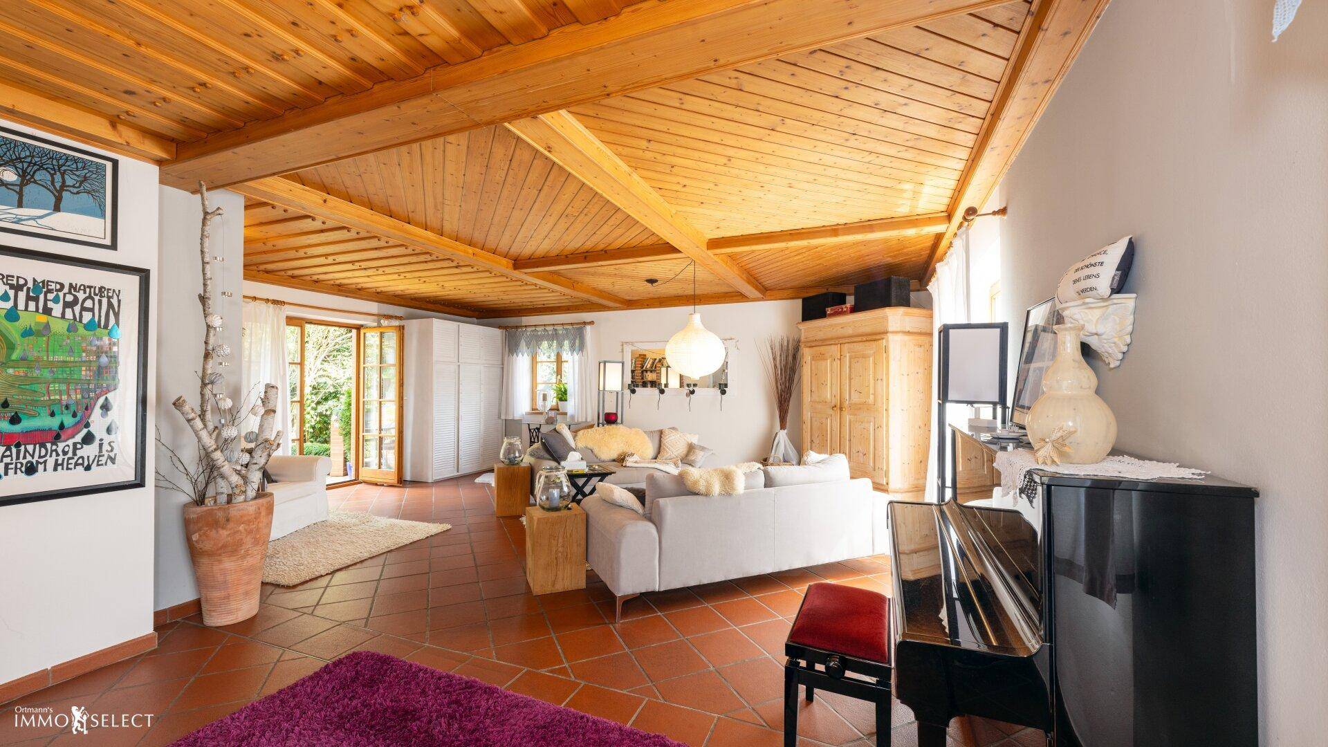 Geräumiges Wohnzimmer mit Holzbalkendecke, Terrakottaboden und einem eleganten Klavier.