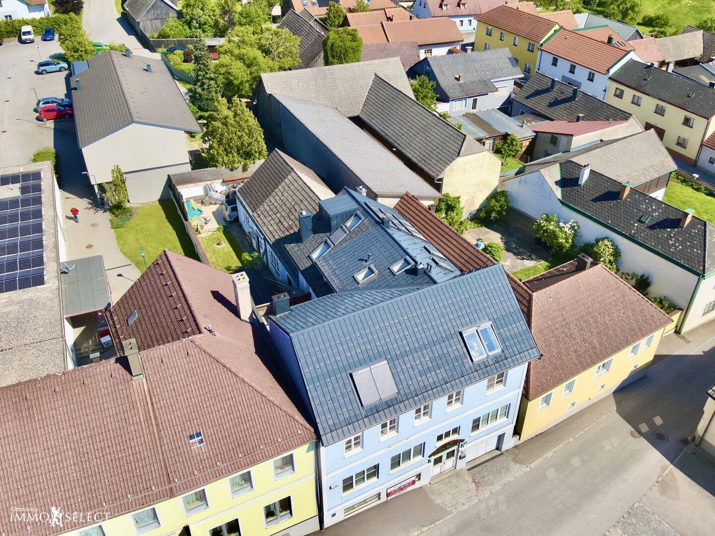 Weitwinkel-Luftaufnahme eines Wohngebiets mit dem hellblauen Gebäude im Vordergrund und weiteren Häusern.