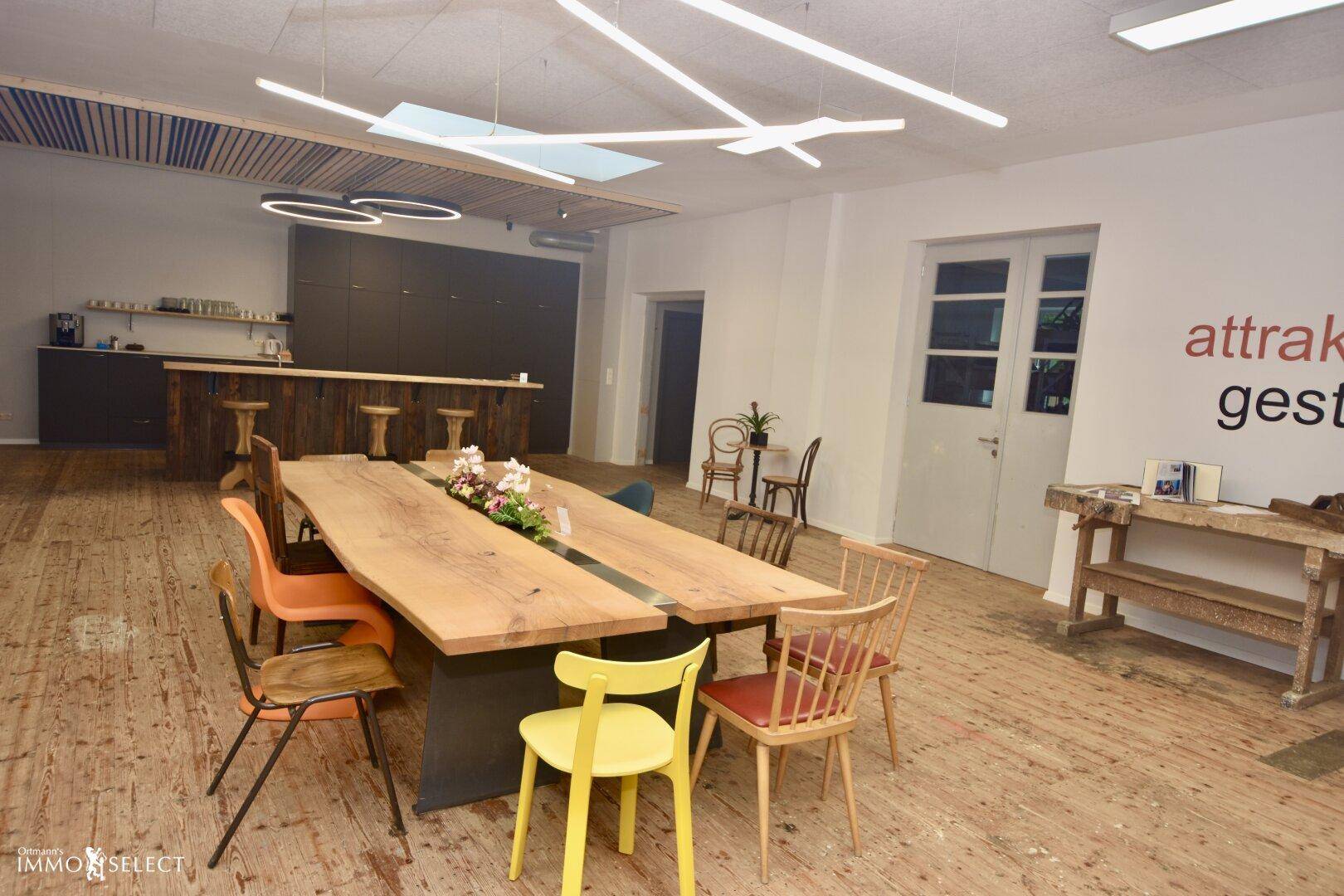 Geräumiger Essbereich mit einem großen Holztisch, bunten Stühlen und moderner Deckenbeleuchtung.