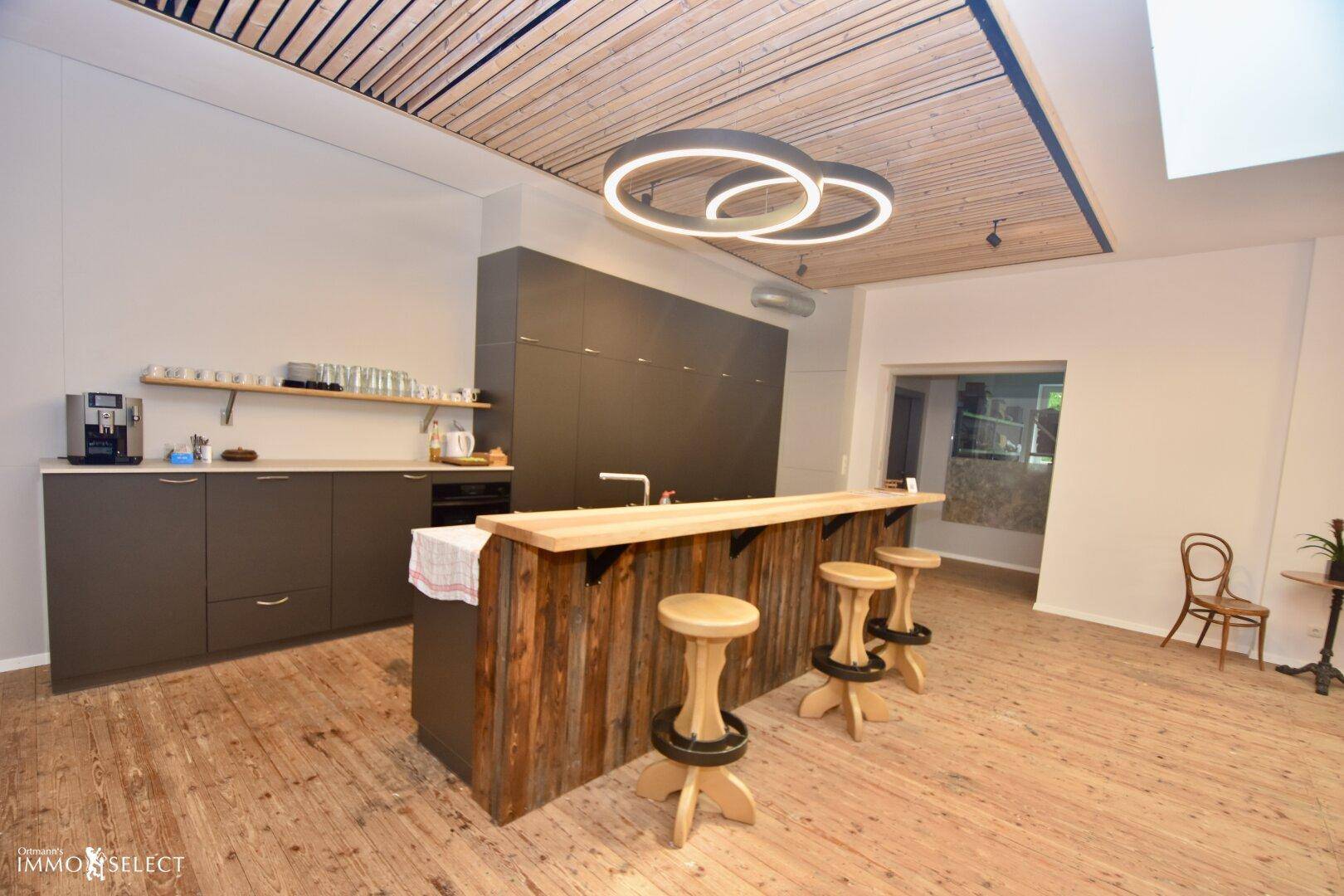 Moderne Küche mit dunklen Schränken, Holztheke und Barhockern, kombiniert mit einem Essbereich.