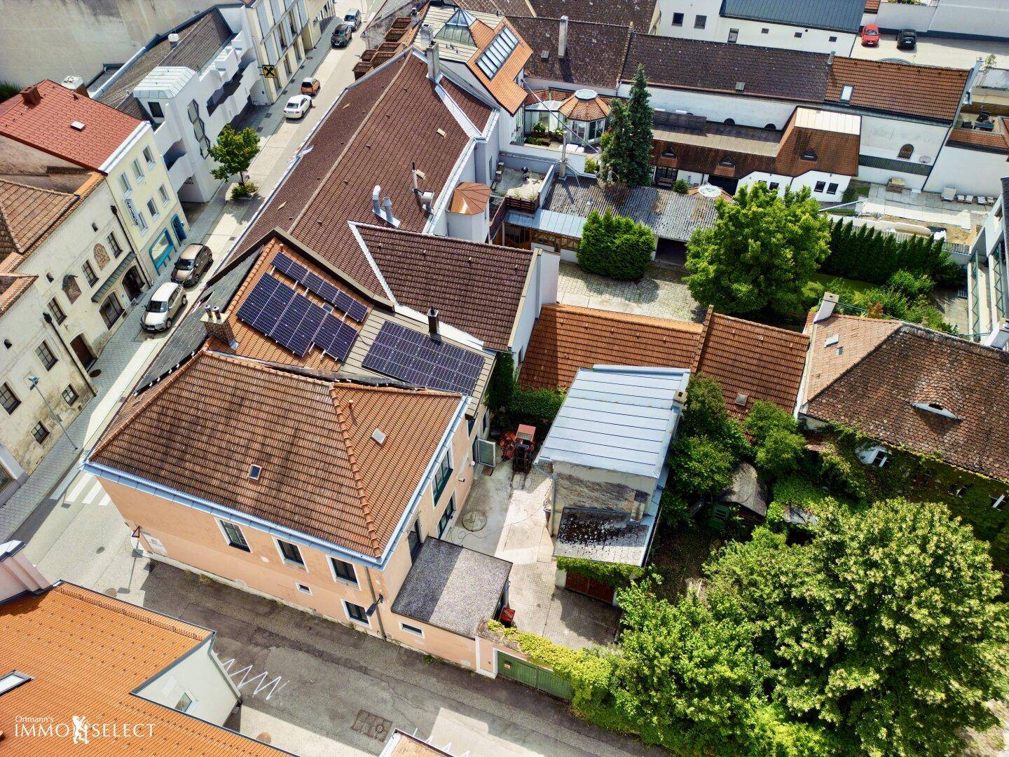 Luftaufnahme eines Gebäudes mit Solaranlagen auf dem Dach und einem grünen Innenhof.