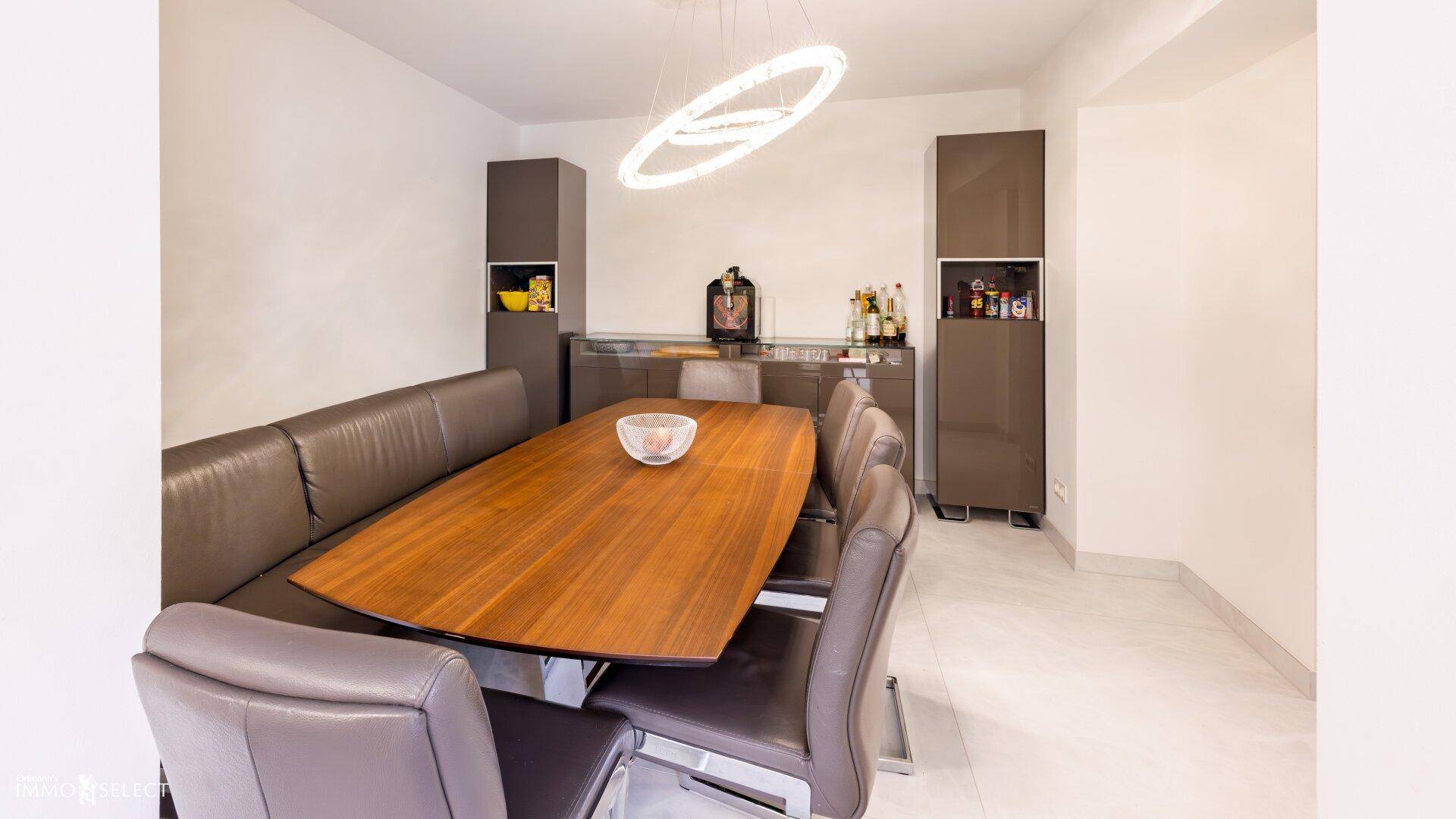 Moderner Essbereich mit Holztisch, Ledersitzbank und eleganten Hängeschränken.