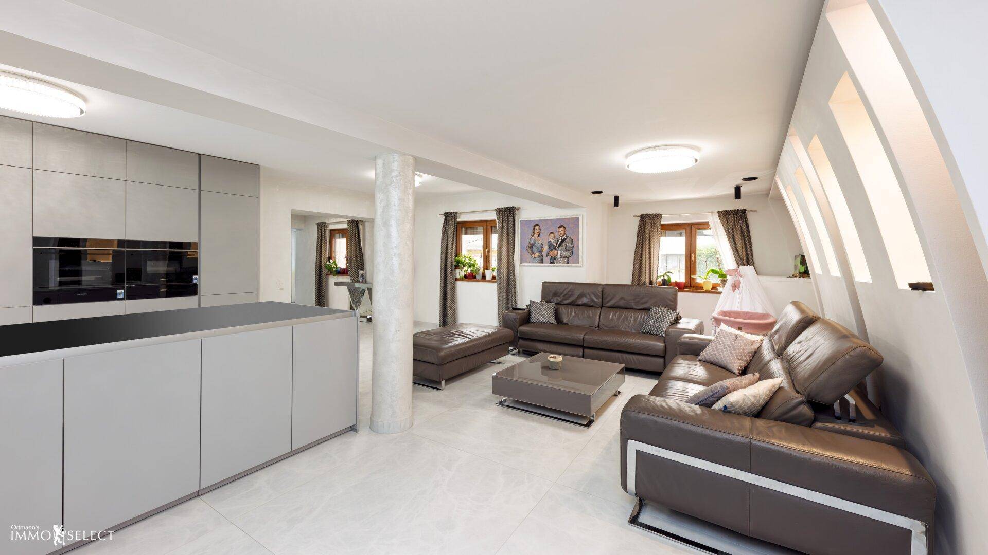 Geräumiger Wohnbereich mit Ledersofas und offener Küche, hell und modern gestaltet mit hohen Decken.