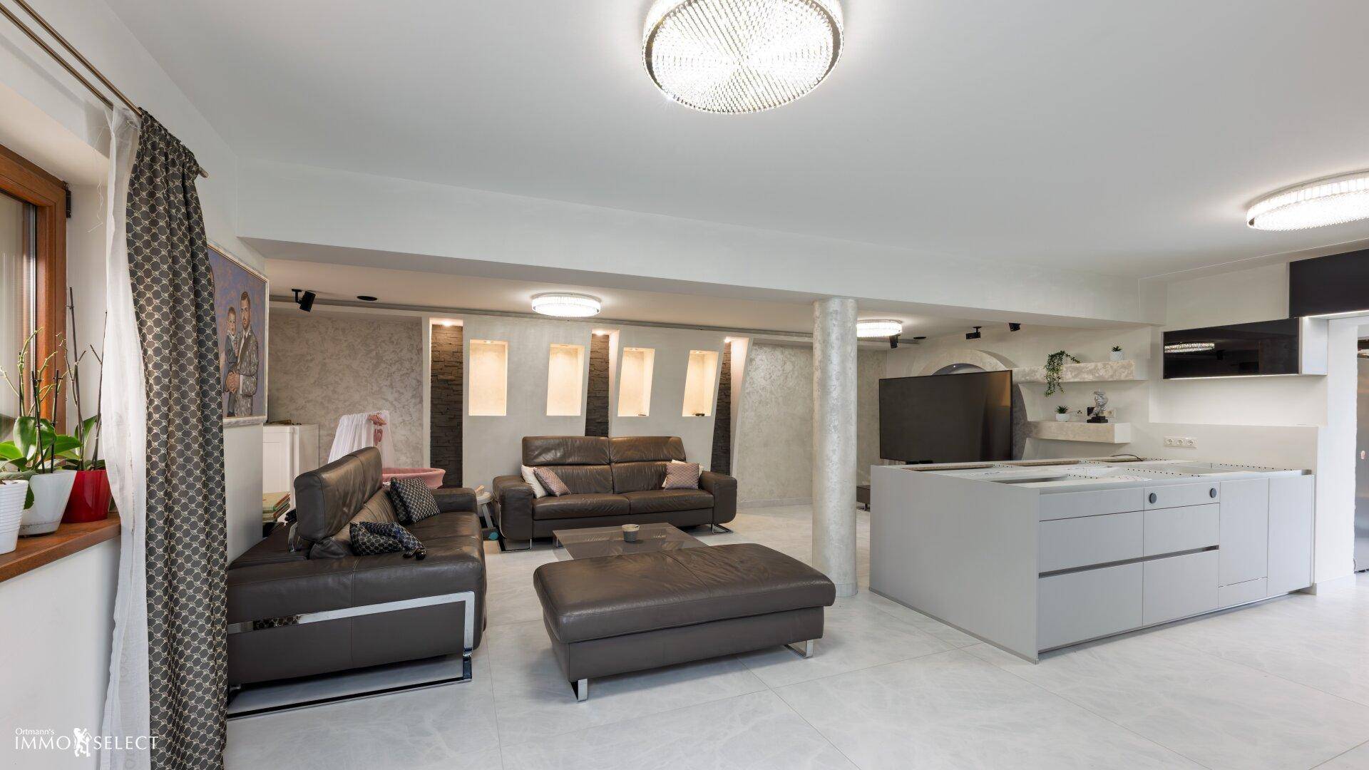 Heller Wohnbereich mit Ledersofas und integrierter Küche, ideal für geselliges Beisammensein und Entspannung.